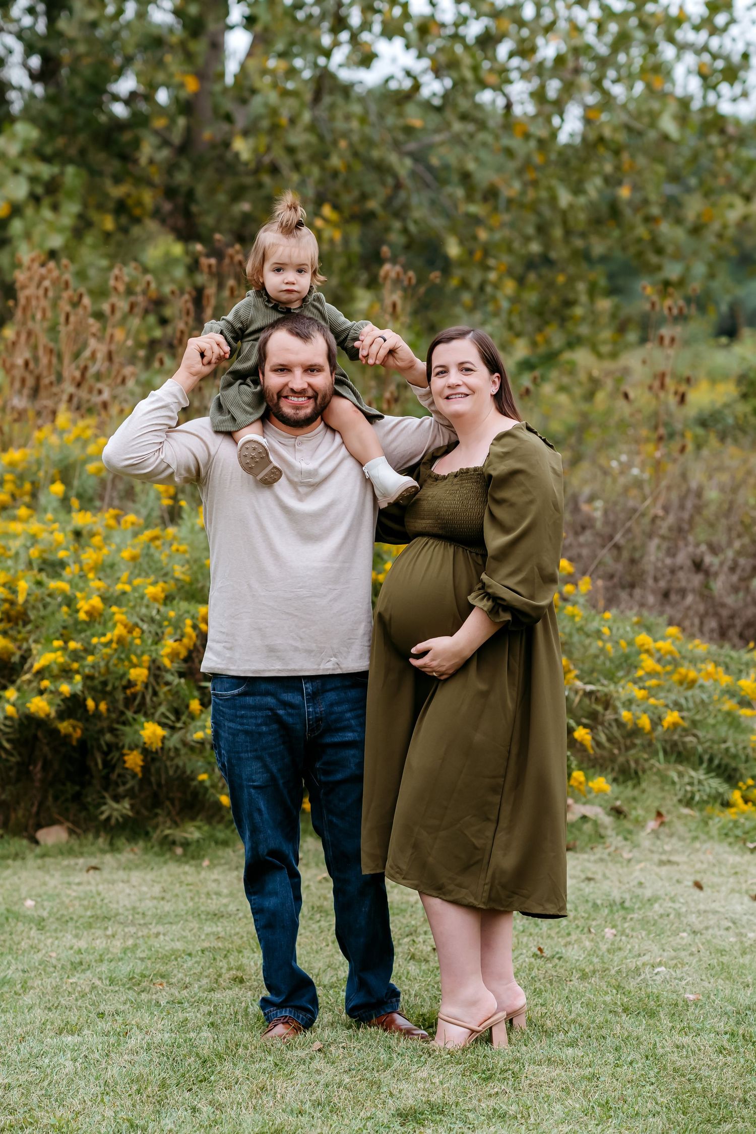 A couple shares playful moments in a field of yellow wildflowers on a sunny autumn day.