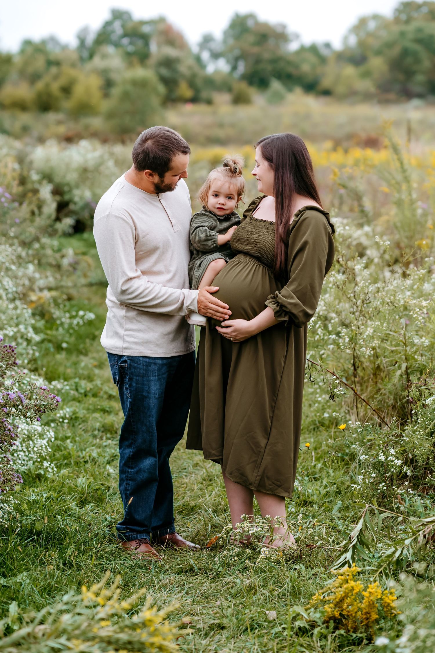 A family shares a tender moment together in a wildflower meadow during autumn.