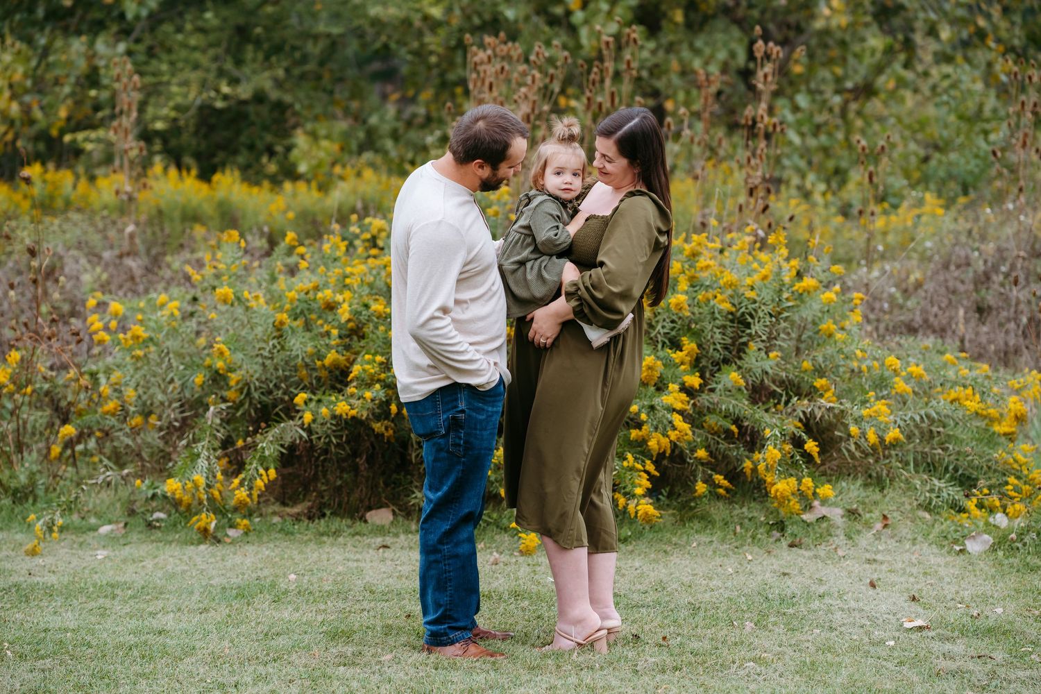 A couple shares tender moments in a field of yellow wildflowers during an autumn engagement photo session.