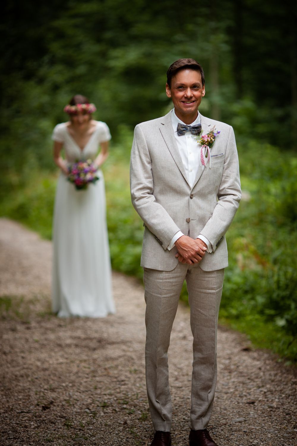 A couple shares a romantic first look moment on a wooded path during their wedding day.
