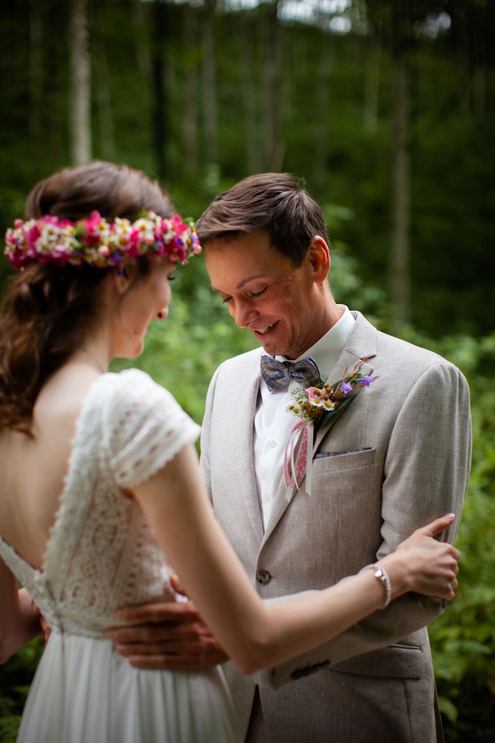 Wedding couple shares intimate moments in a wooded outdoor setting with natural greenery.