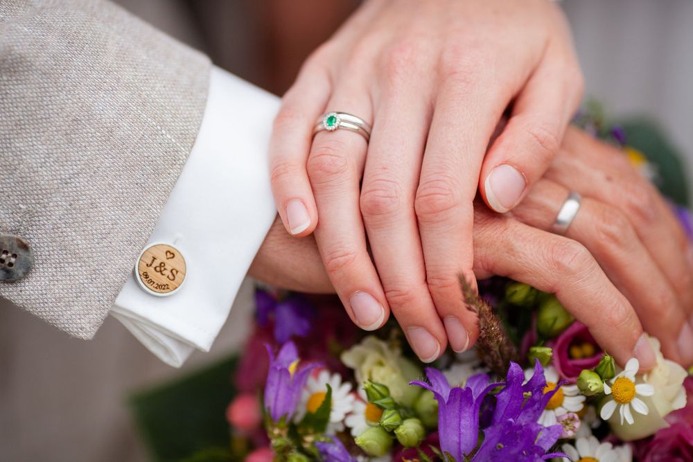 Close-up of hands holding a vibrant purple and green floral wedding bouquet.