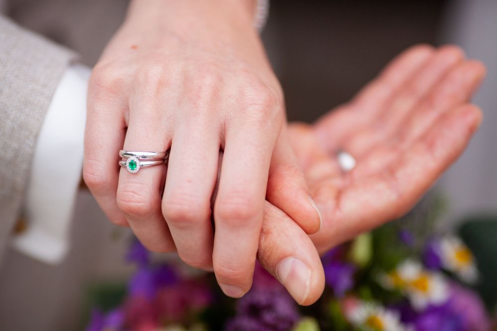 Close-up of hands exchanging wedding rings during a ceremony.