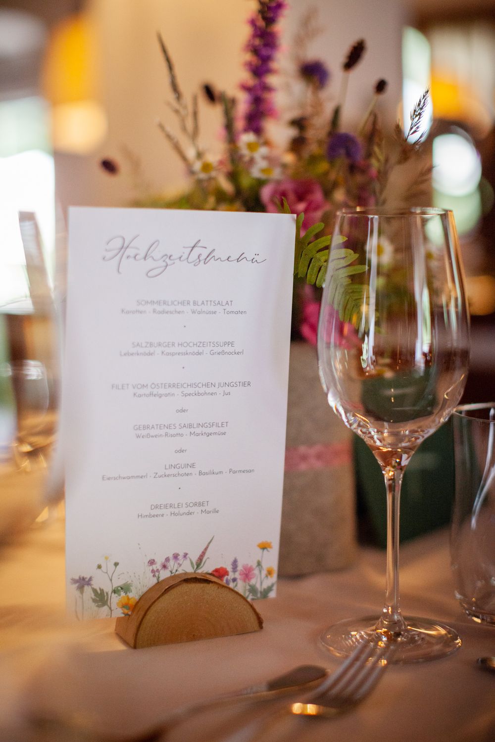 Elegant wedding reception table settings with menu cards and wine glasses.
