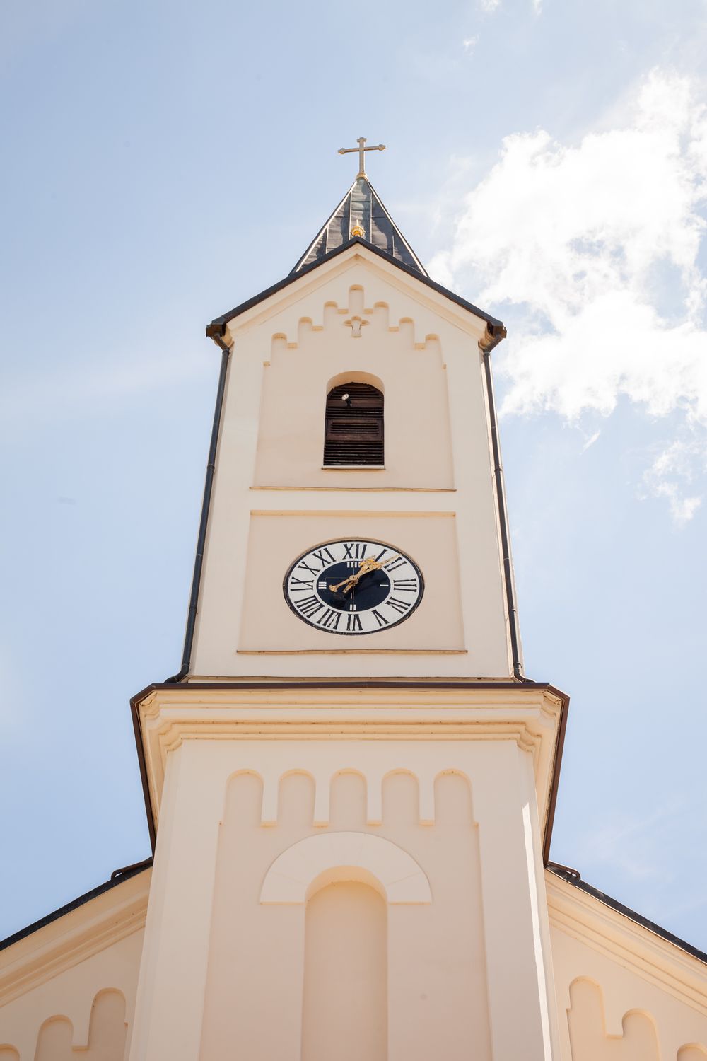 White church steeple with clock and cross against blue sky shown from three different angles in architectural detail.