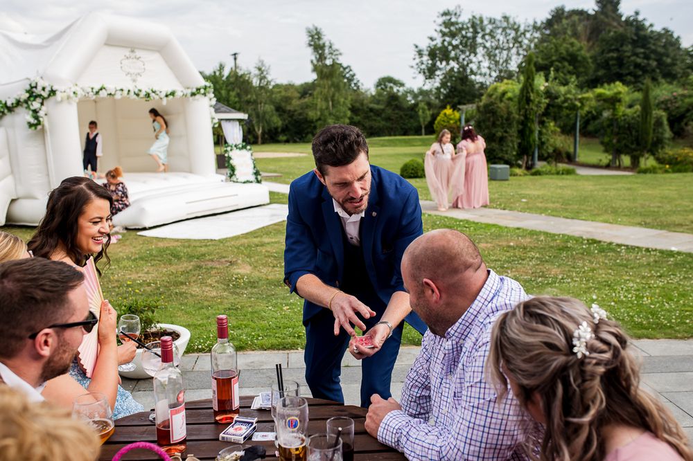 Wedding guests enjoy refreshments at outdoor tables during daytime reception.