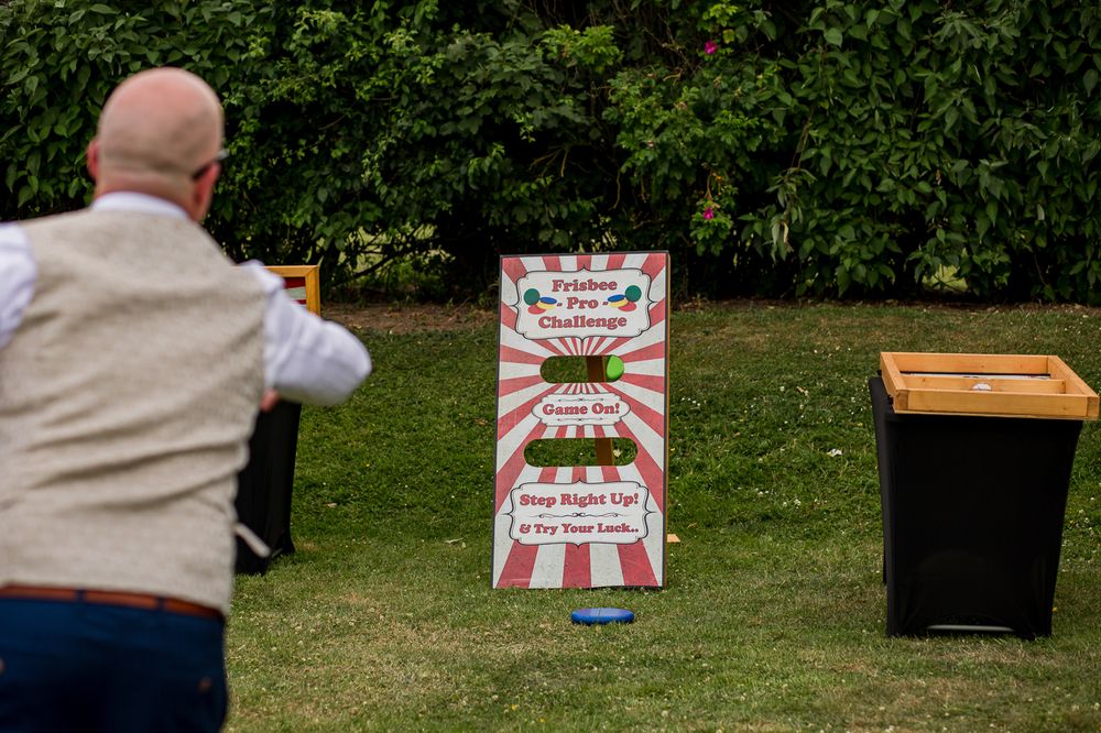 Garden games and activity stations set up on lawn at outdoor wedding reception.