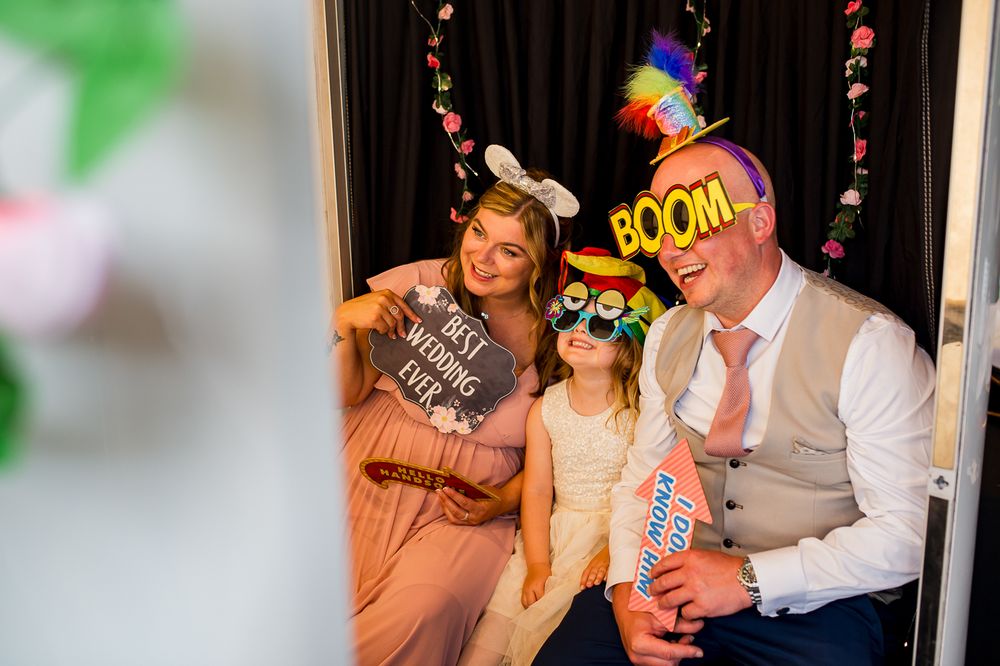 Wedding party guests having fun with colorful photo booth props and signs.