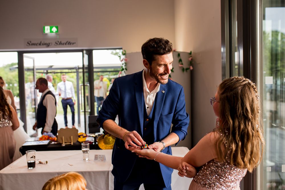 Wedding party guests enjoying drinks and entertainment at an indoor venue.