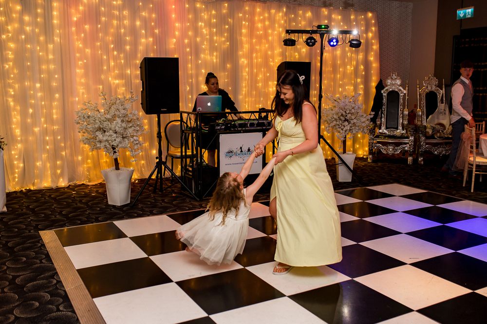 Guests dancing on a black and white checkered floor with twinkle light backdrop.