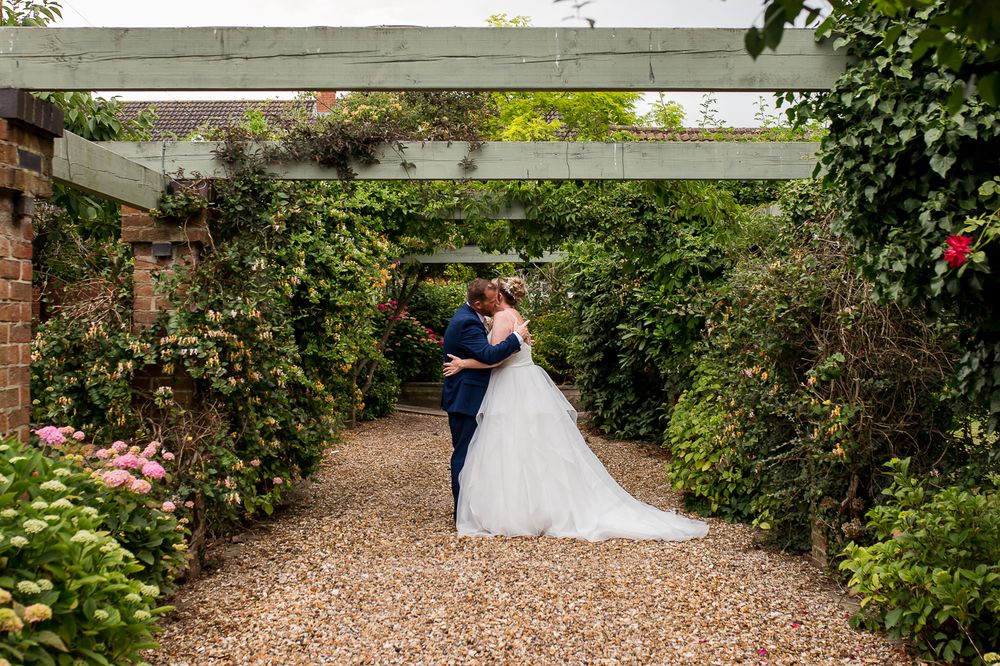 Romantic garden wedding photos with couple surrounded by blooming foliage and natural landscaping.