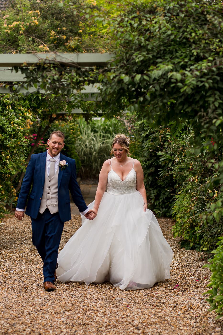 Fun wedding photo series captures couple's joyful moments on gravel garden path.