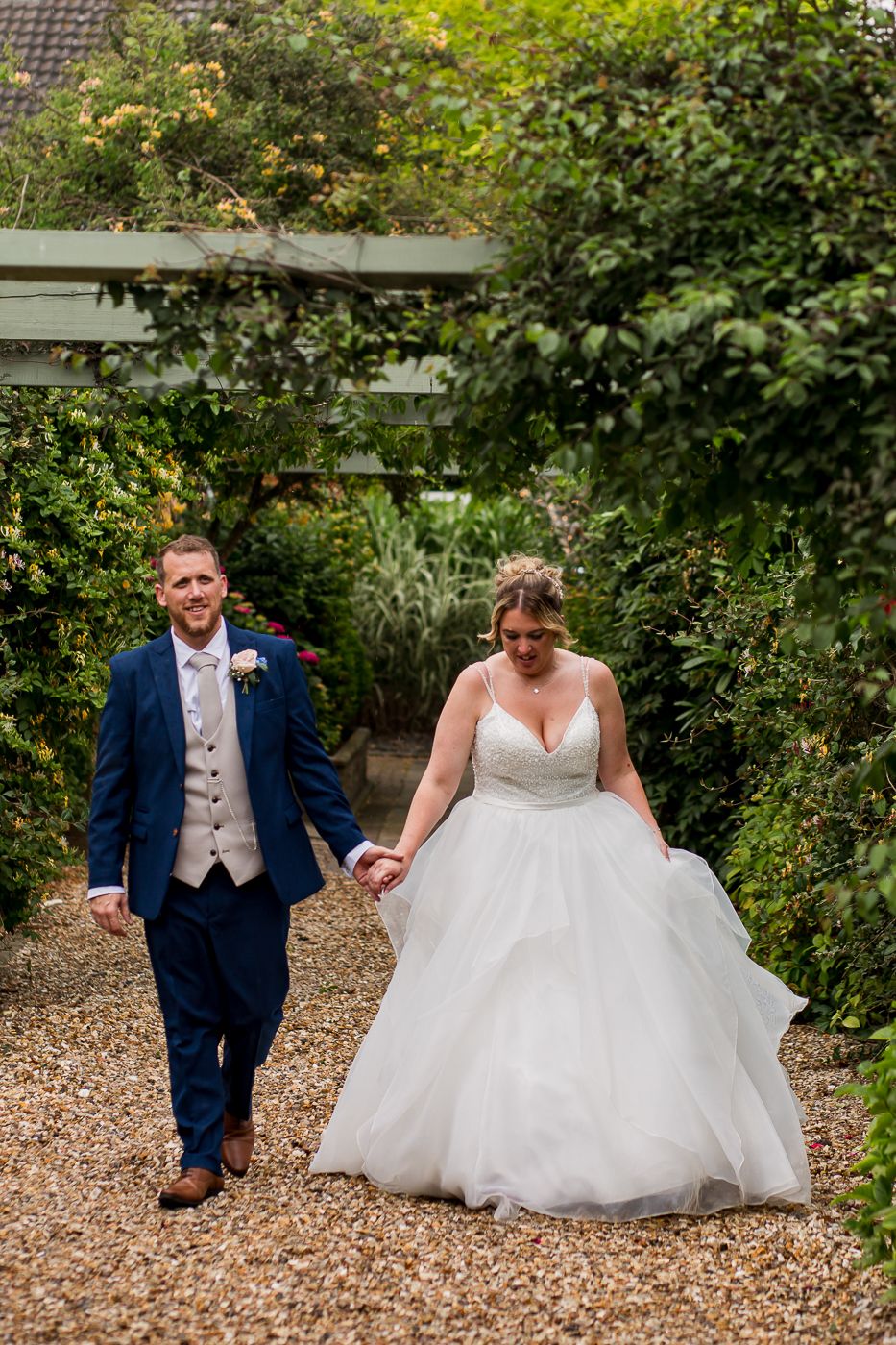 Playful wedding sequence shows couple interacting on garden path surrounded by greenery.