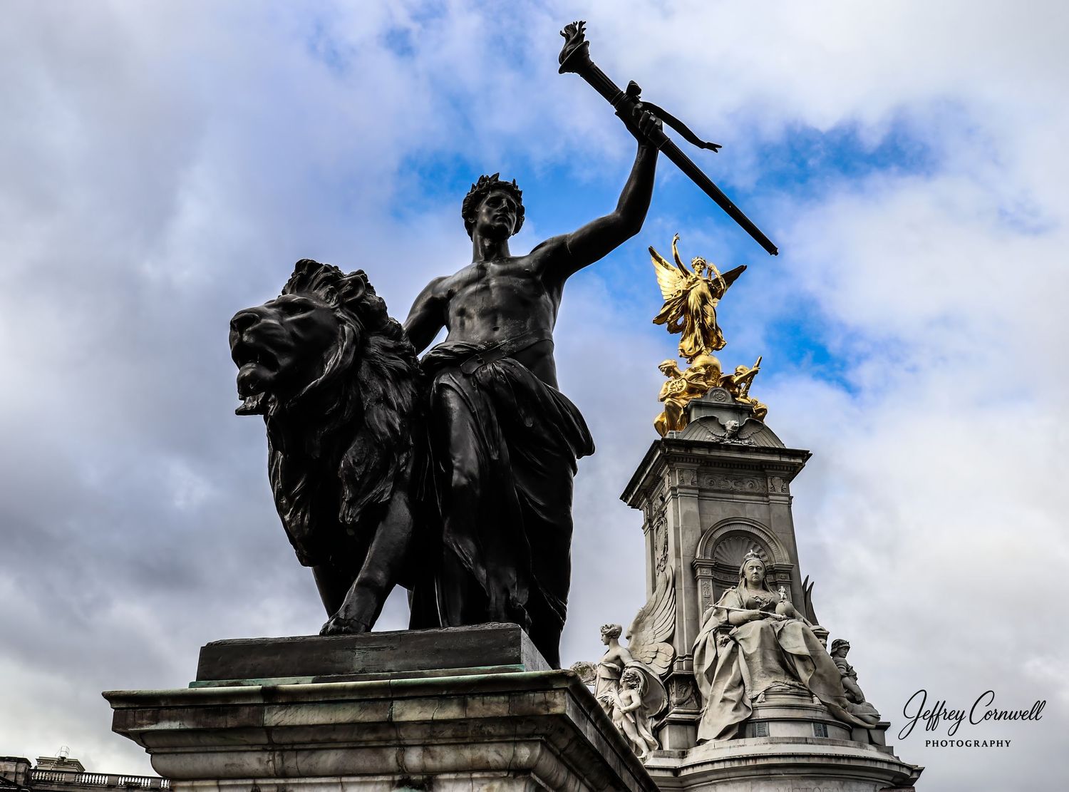 Ornate statues and sculptures adorning a historic building against a cloudy sky.
