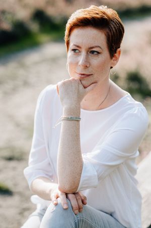 Person in white shirt poses thoughtfully against blurred natural background in artistic photo series.