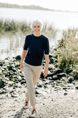 Person in black t-shirt and khaki pants walking on rocky terrain in bright natural lighting.
