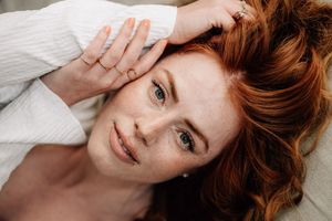 Person with red hair lying on white bedding in a series of relaxed poses.