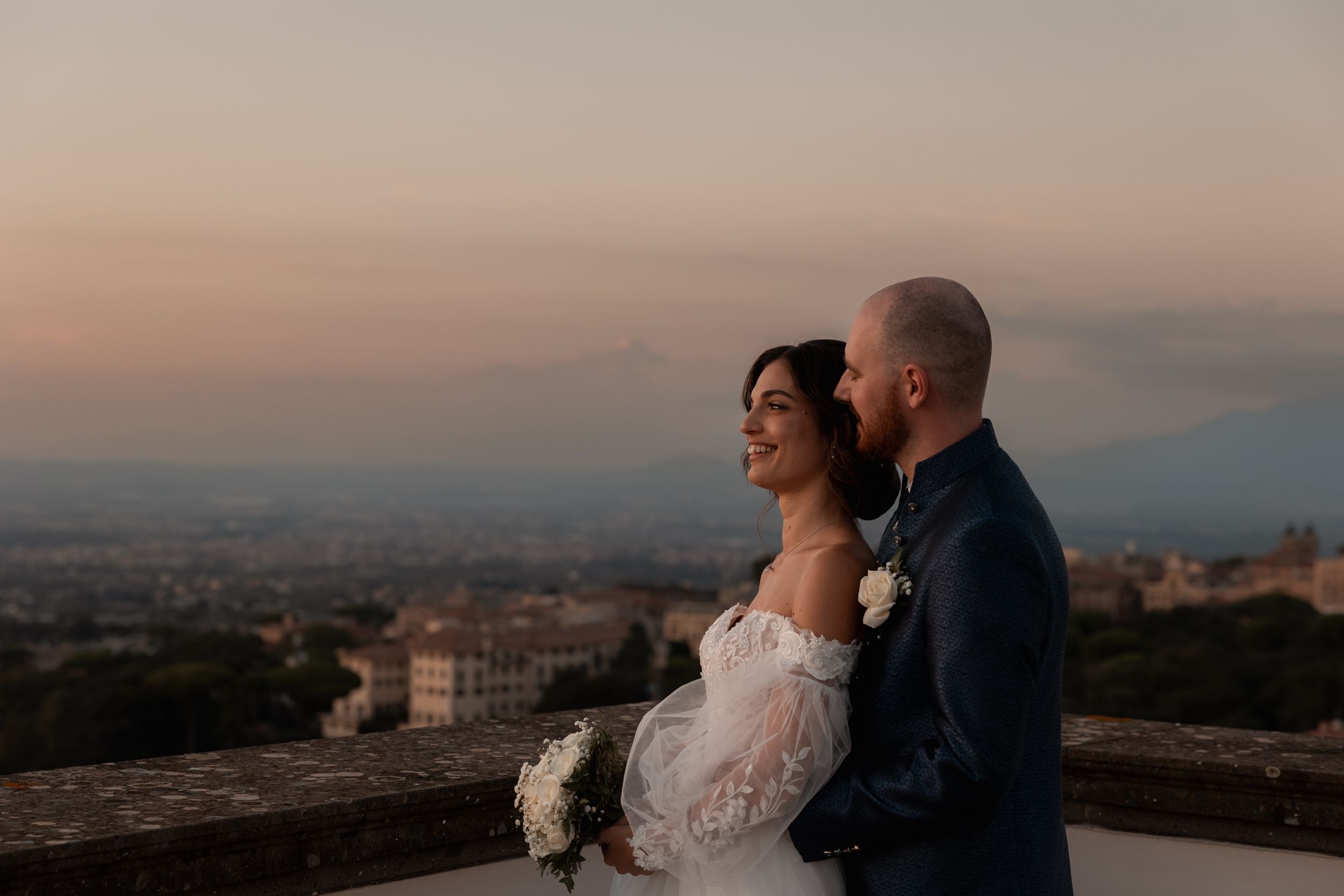 Romantic sunset wedding photos captured at a scenic overlook with city views in the background.