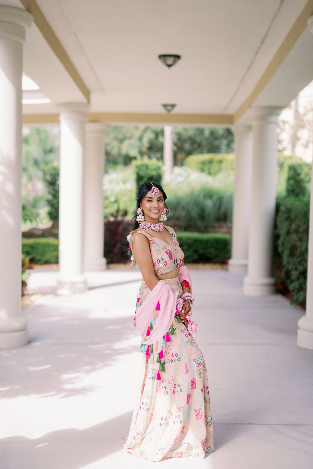 People in matching floral dresses pose and twirl under a white columned walkway.