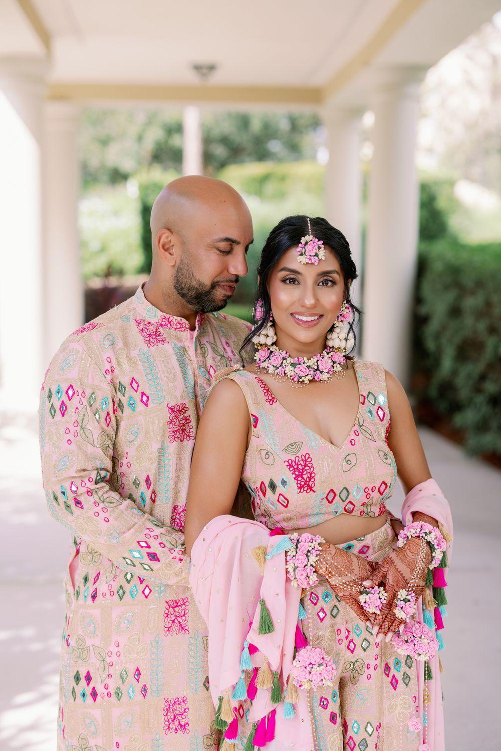 Couple in matching floral outfits share intimate moments during their traditional Indian wedding photoshoot.