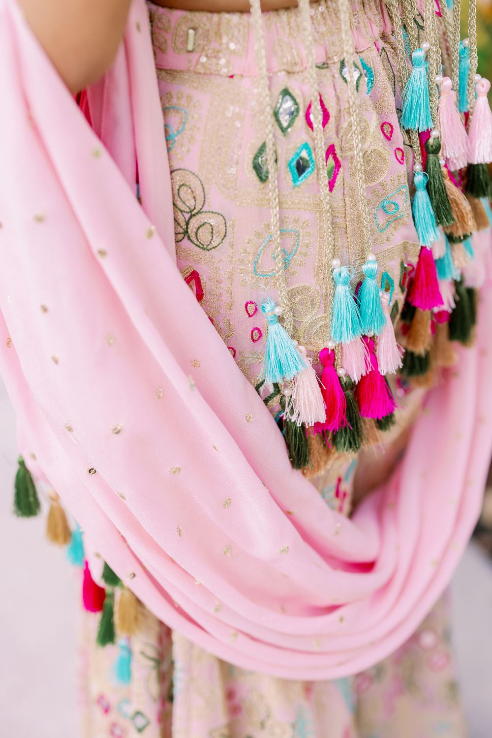 Decorative pink fabric draping with colorful tassels in turquoise, pink and gold hanging along the edge.