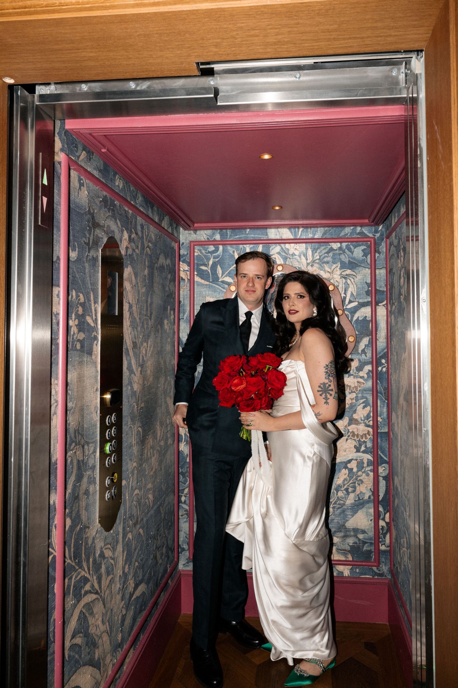 Romantic wedding couple embraces in front of elegant stone building with ornate architectural details and windows.