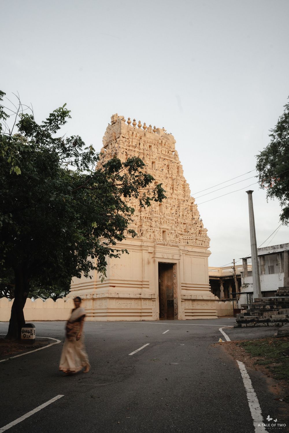 Ancient temple with ornate gopuram architecture captured at dusk with empty parking area in the foreground.