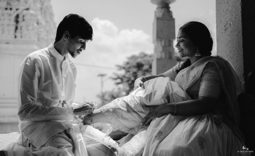 Black and white photo of a young couple in traditional Indian attire sharing a tender moment at a temple.