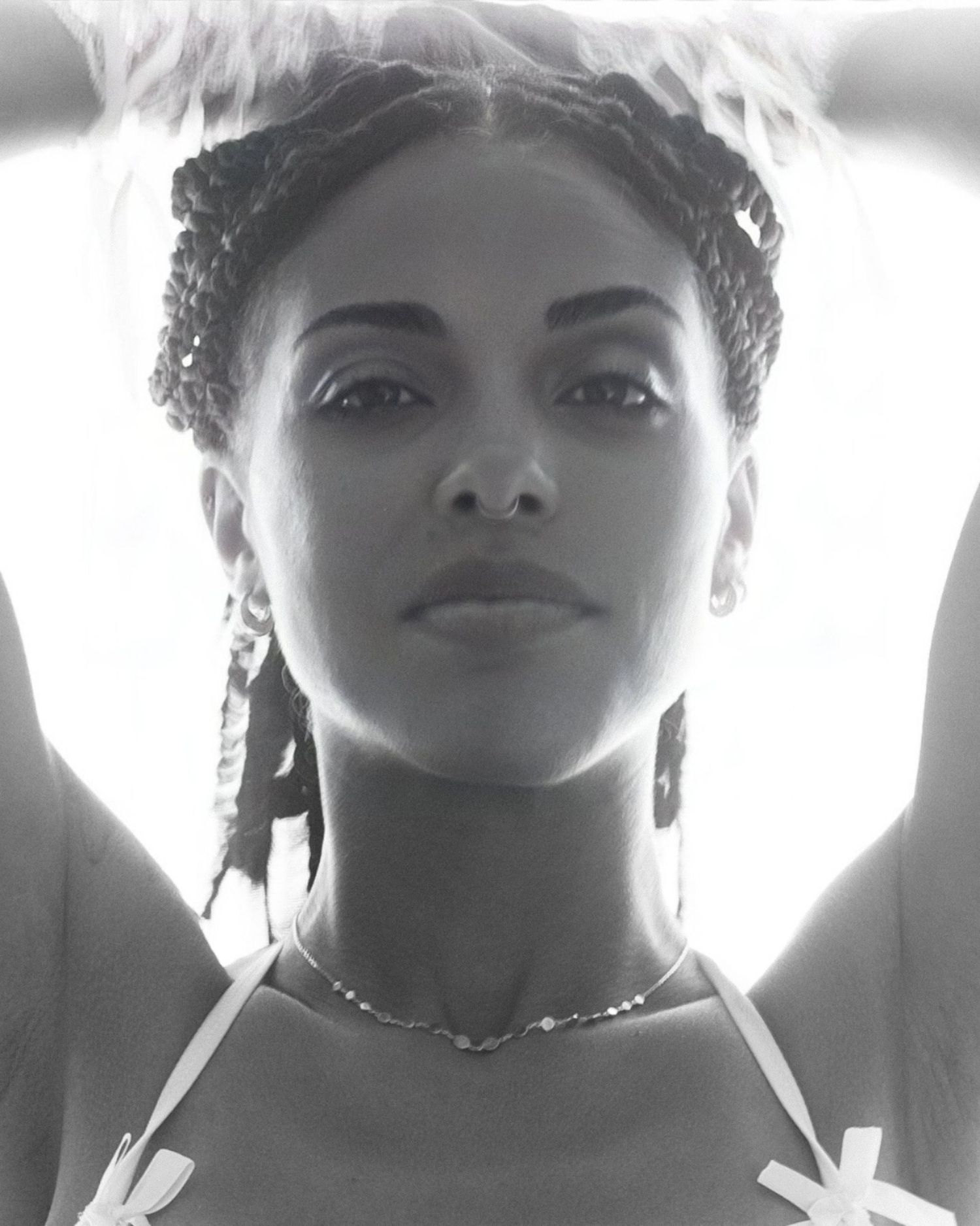 Artistic black and white portrait with dramatic backlighting showing braided hairstyle and jewelry.