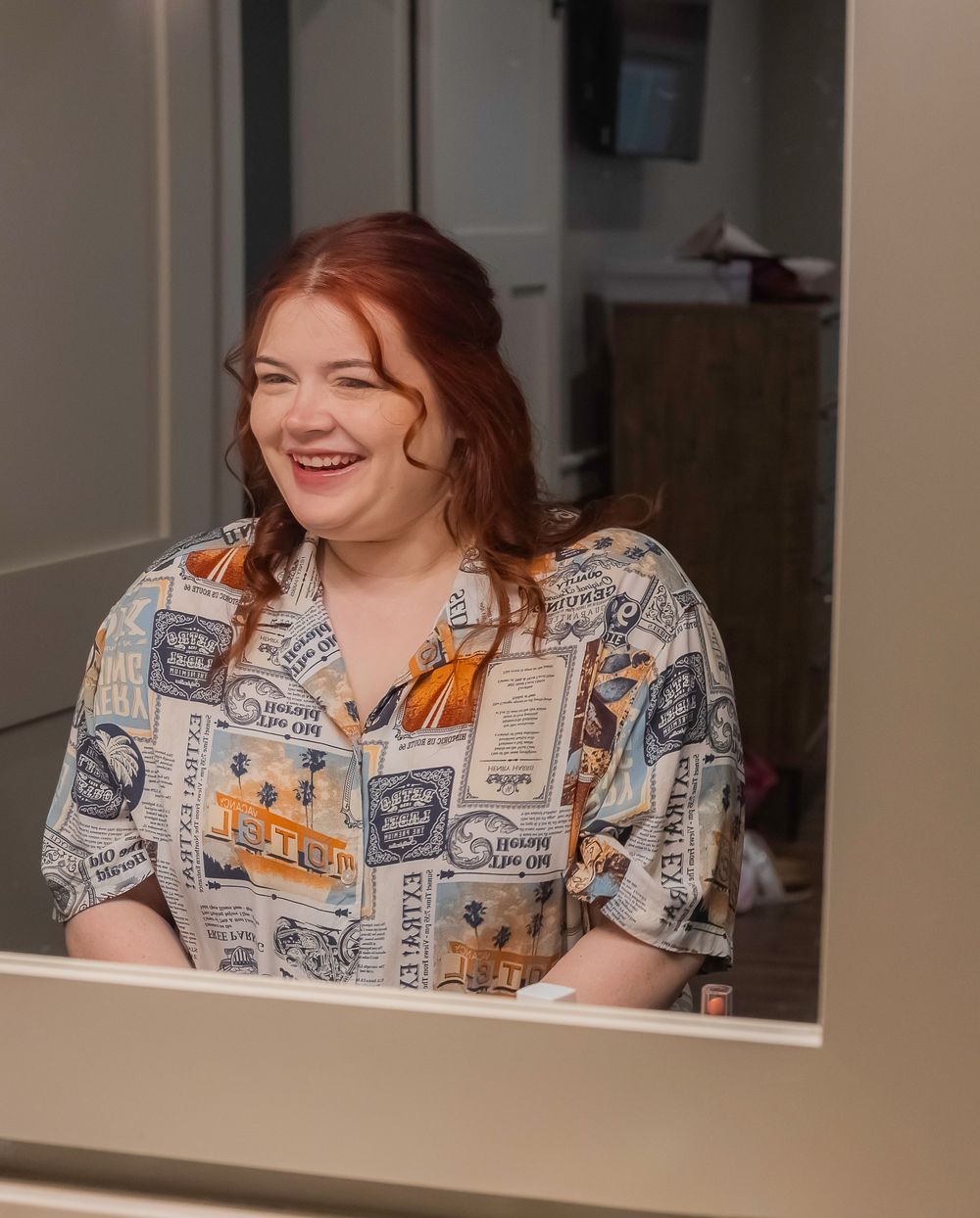 Person wearing a novelty print shirt with travel stamps pattern sits indoors.