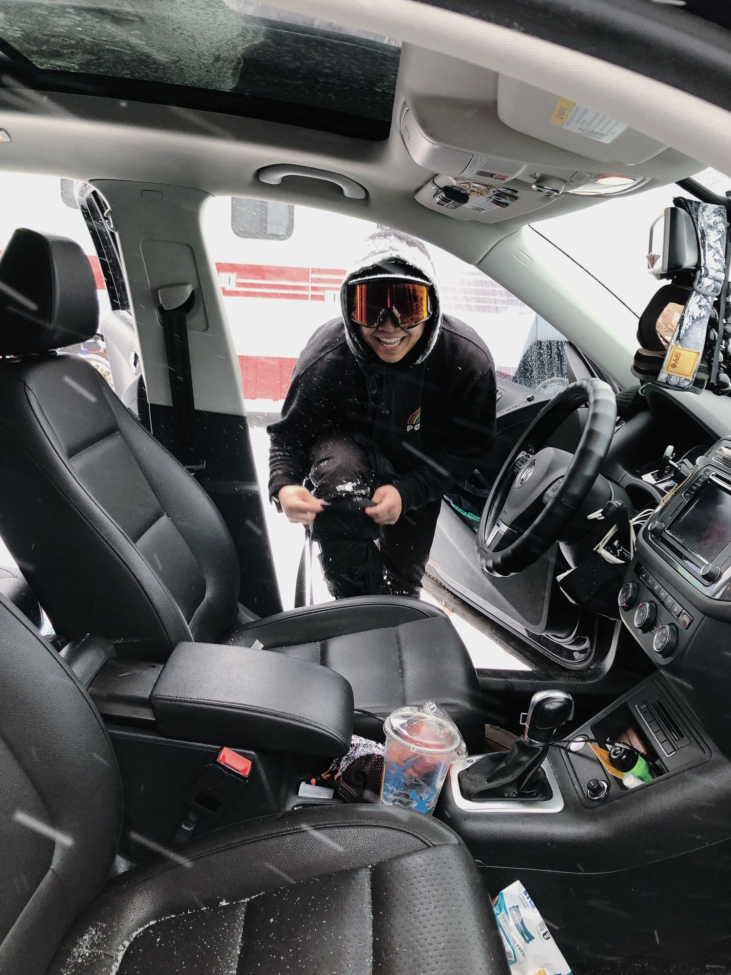Interior view of a vehicle showing someone in winter gear adjusting settings in the black leather front seats.