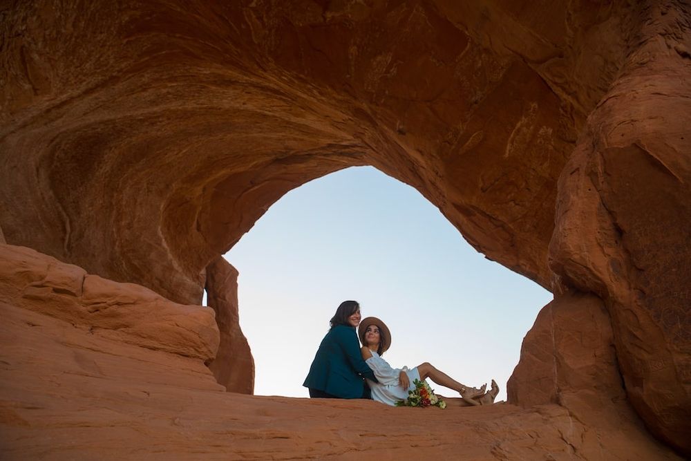A series of red rock canyon arches and formations against a bright blue desert sky.