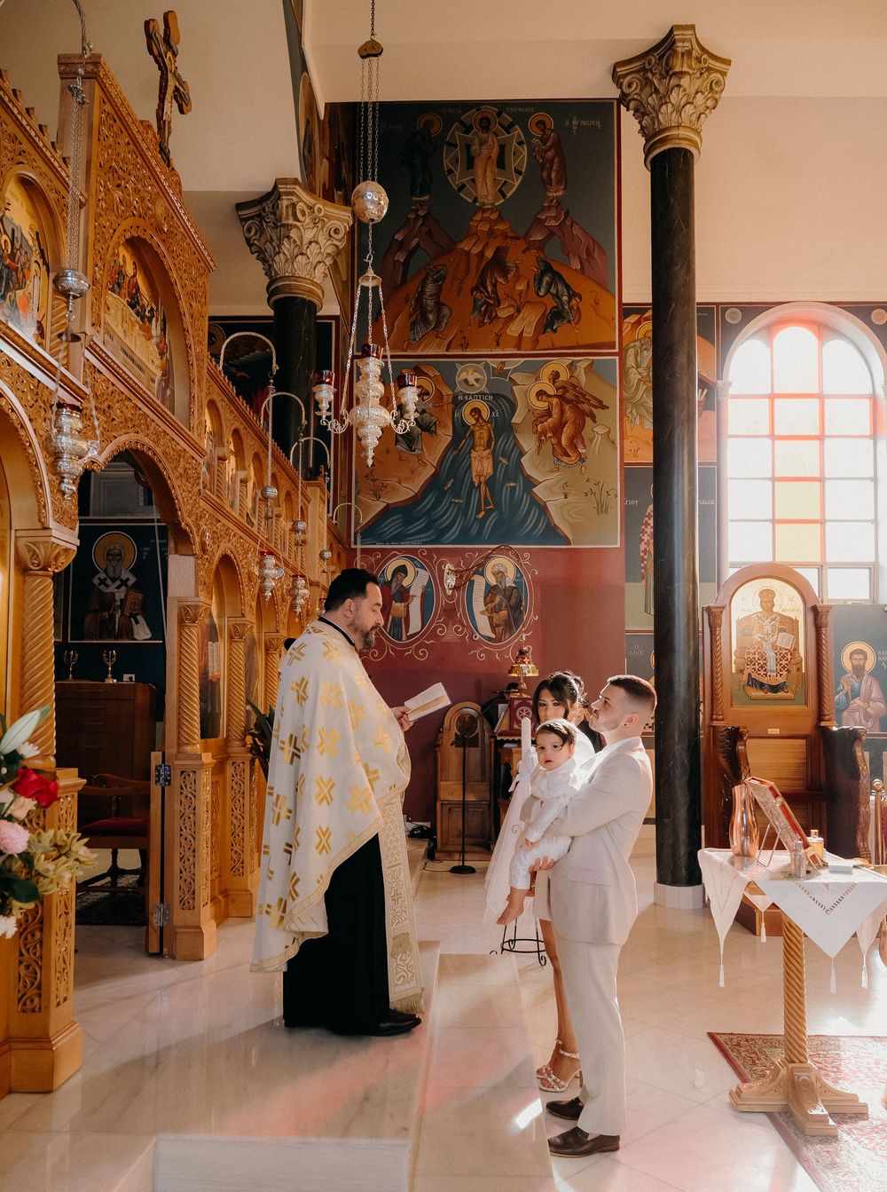 Panoramic view of a traditional Orthodox church interior with ornate gold decorations and arched windows during a ceremony.