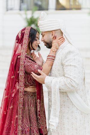 A couple in traditional South Asian wedding attire share intimate moments during their ceremony.