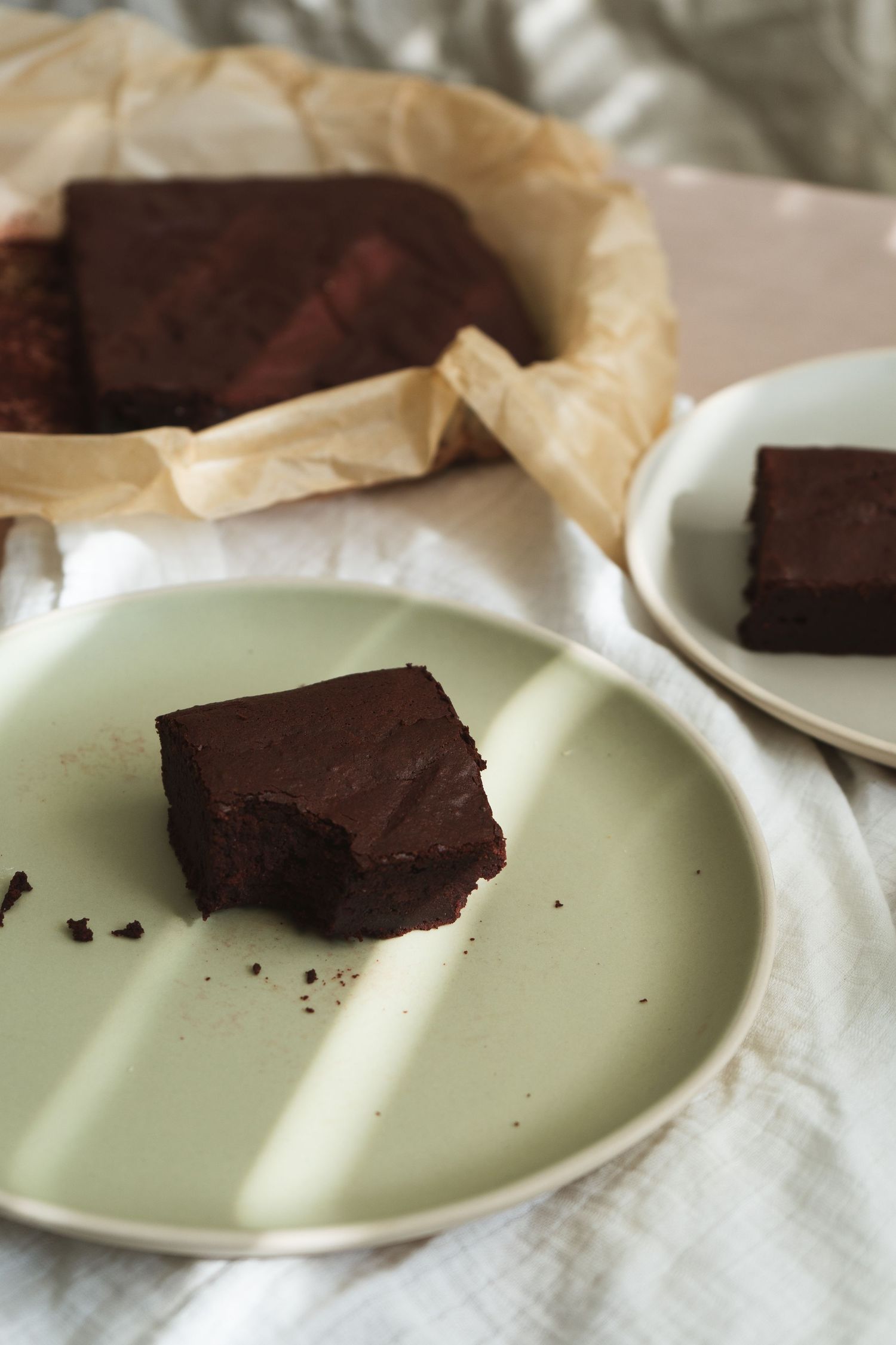 Lifestyle product photo with natural light of luxury tableware with brownies, sage green plate in sunlight