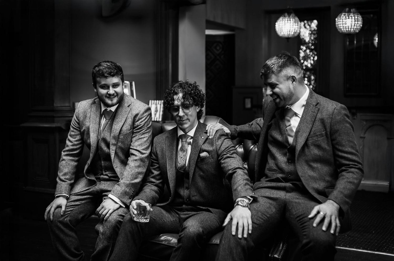 Groomsmen in dark suits share candid laughing moments in a black and white wedding photo collage.