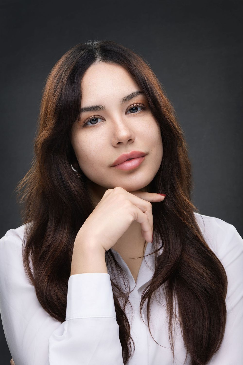 Portrait series of a person with long dark hair wearing a white top against a dark background.