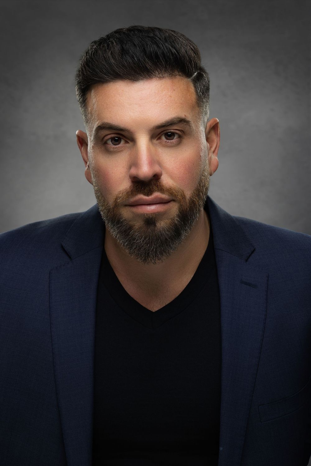 Professional headshot series showing different facial expressions against a dark background wearing a navy blazer.