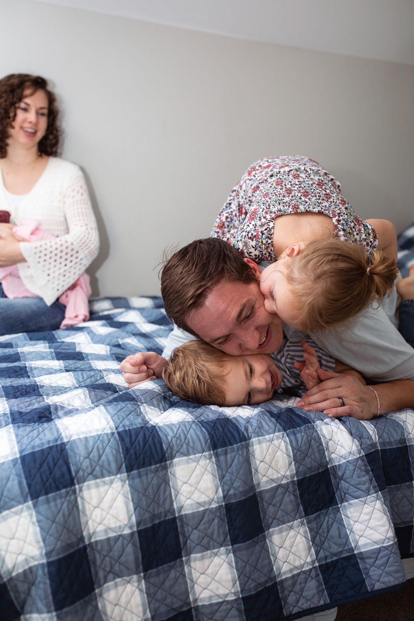 Family shares tender moment together on blue and white checkered blanket during indoor photoshoot.