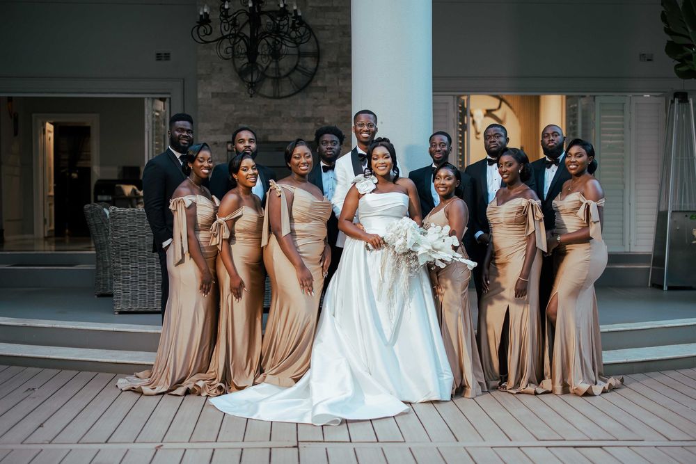 Wedding party poses together on outdoor patio in coordinating neutral-toned formal attire.