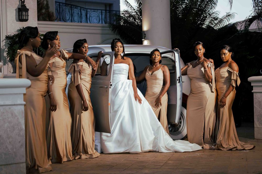 Wedding party in champagne colored dresses and white gowns pose together outdoors.