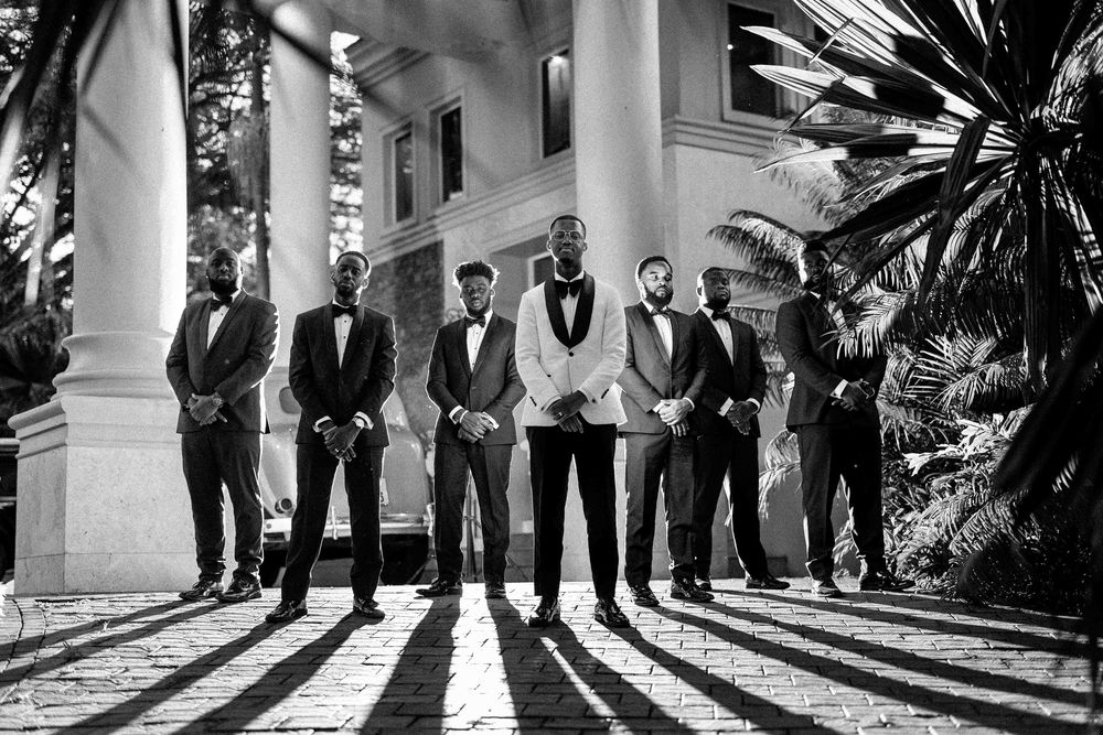 A series of black and white wedding photos showing groomsmen posing on a grand porch with white columns and palm trees.