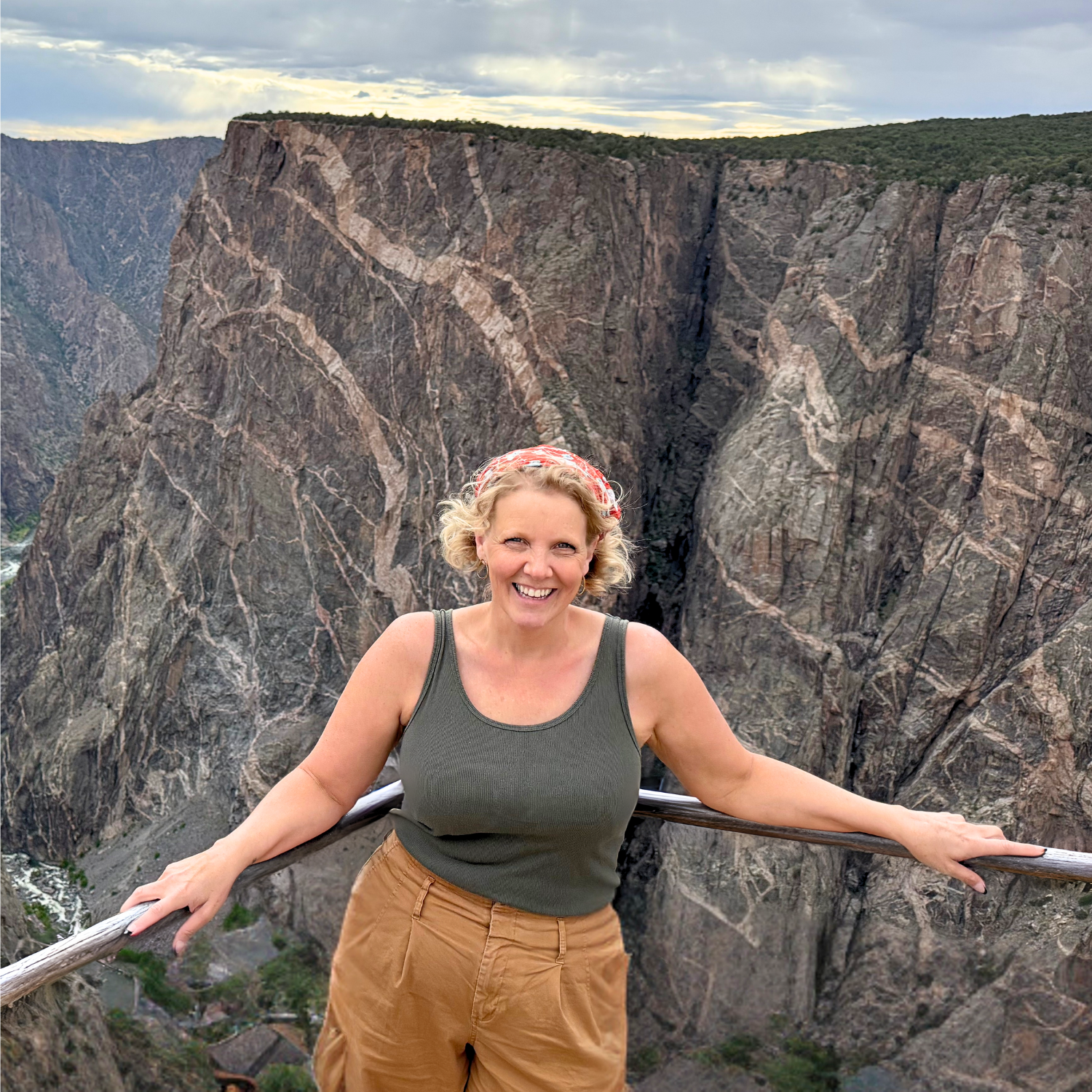 Smiling woman posing at a scenic overlook above the dramatic Black Canyon of the Gunnison in Colorado.