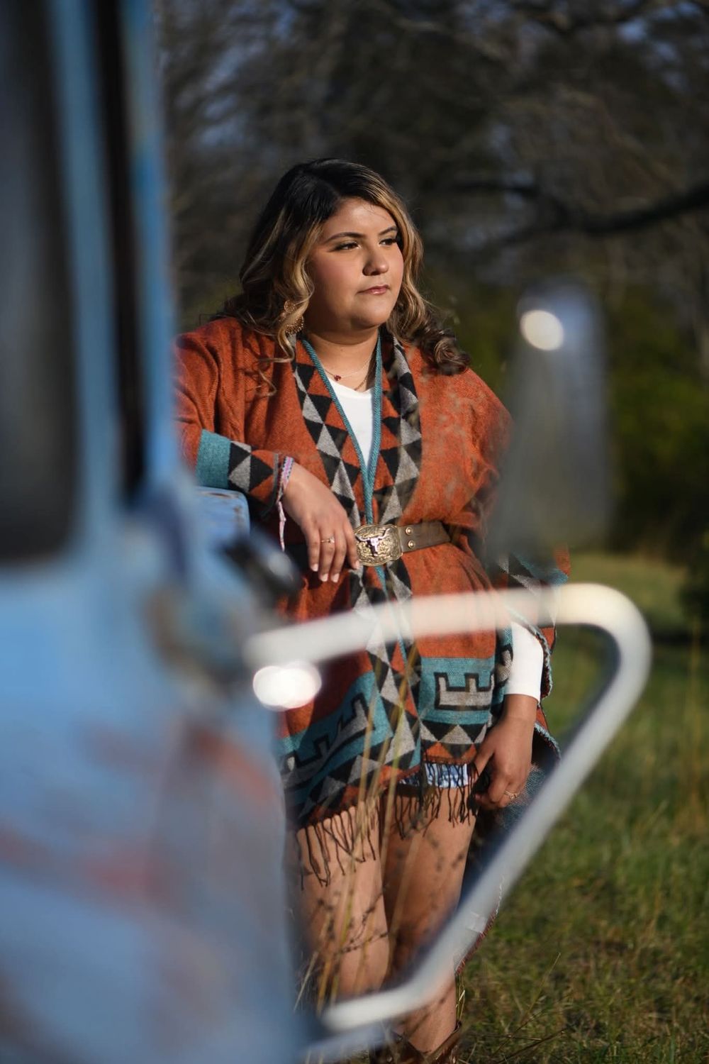 A person in a fringed brown leather jacket poses outdoors in a series of artistic portrait shots at dusk.