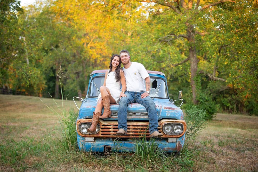 Vintage blue pickup truck parked in autumn scenery with warm fall foliage and golden afternoon light.