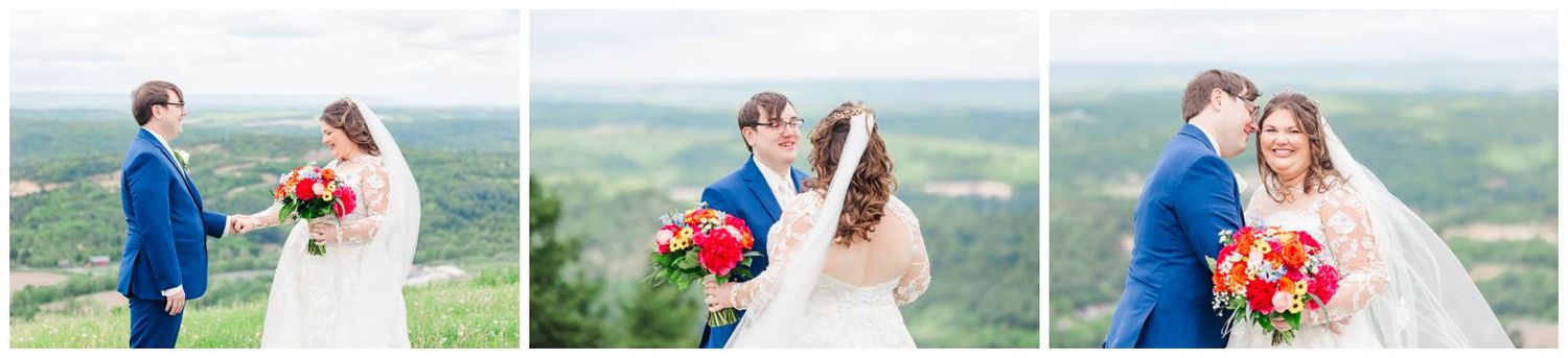 Couple poses intimately against foggy mountain backdrop in blue and white wedding attire with vibrant red bouquet.