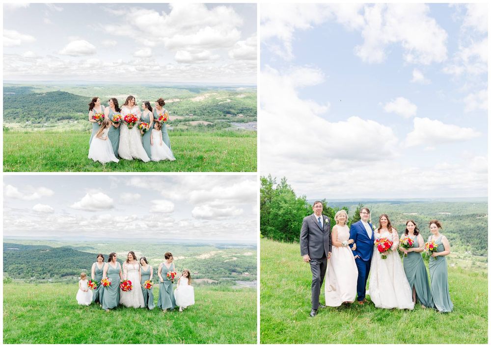 Group wearing blue and white dresses stands on hilltop overlooking scenic green valley landscape on sunny day.