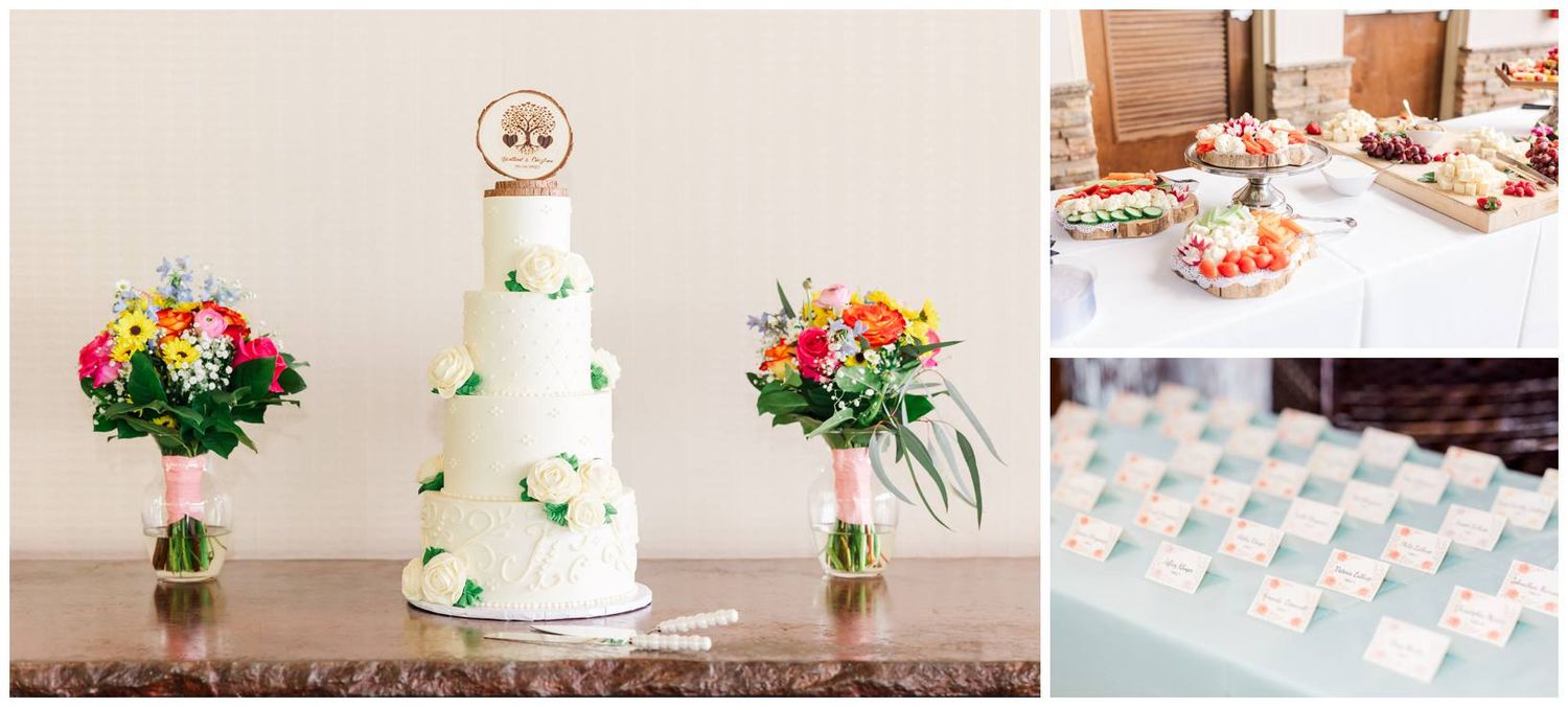 A three-tier white wedding cake decorated with green butterflies sits between two floral arrangements on a wooden table.