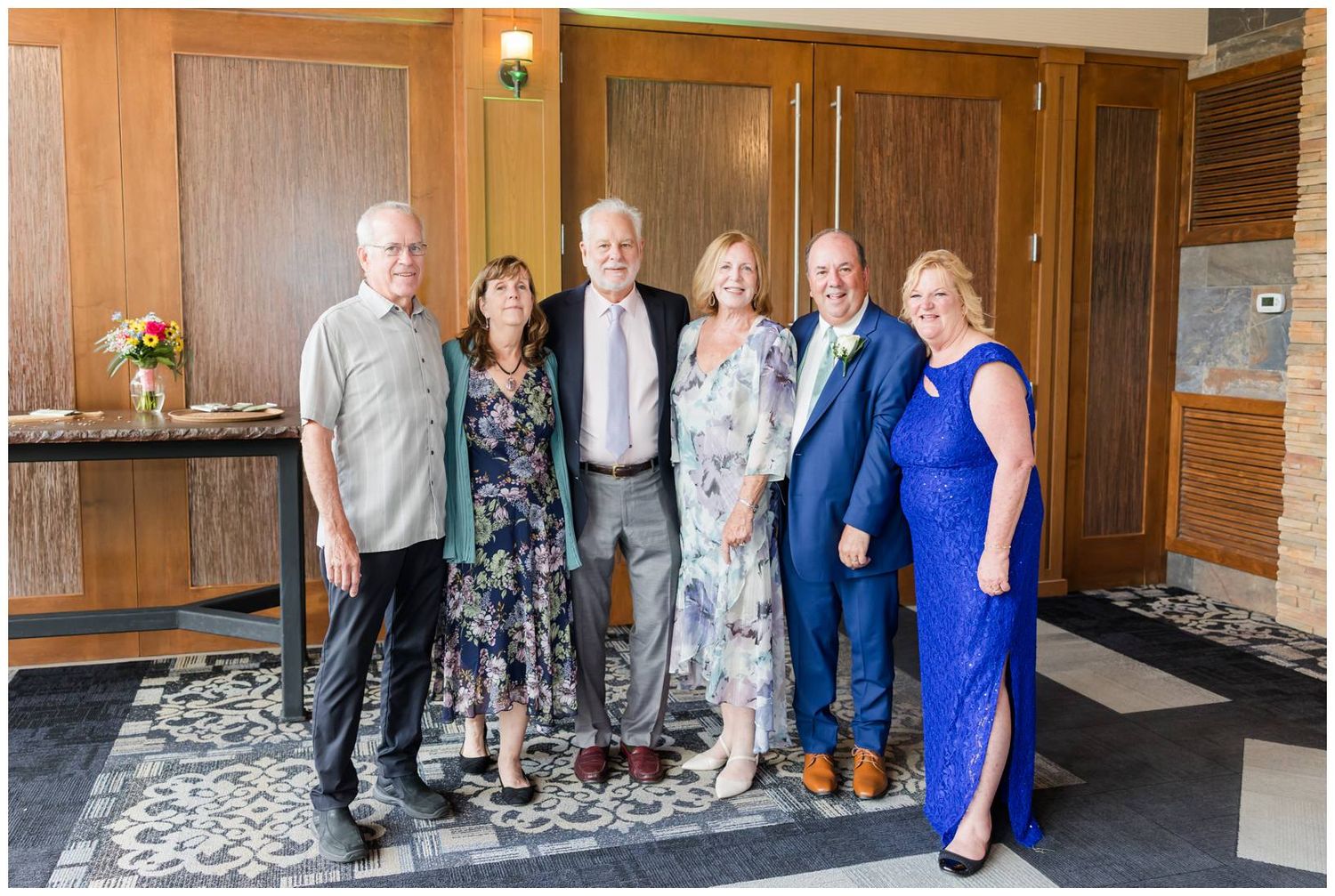 A group of people poses together on a carpet in front of wooden doors at a formal gathering or celebration.