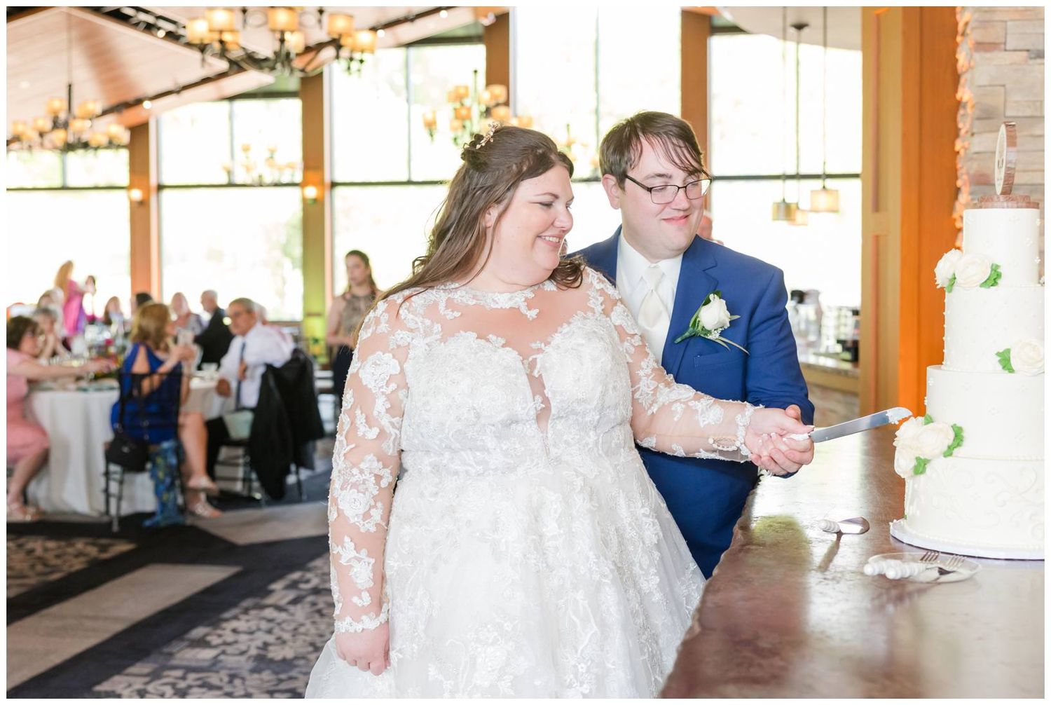 Couple celebrates at their wedding reception in a rustic venue with brick walls and large windows.